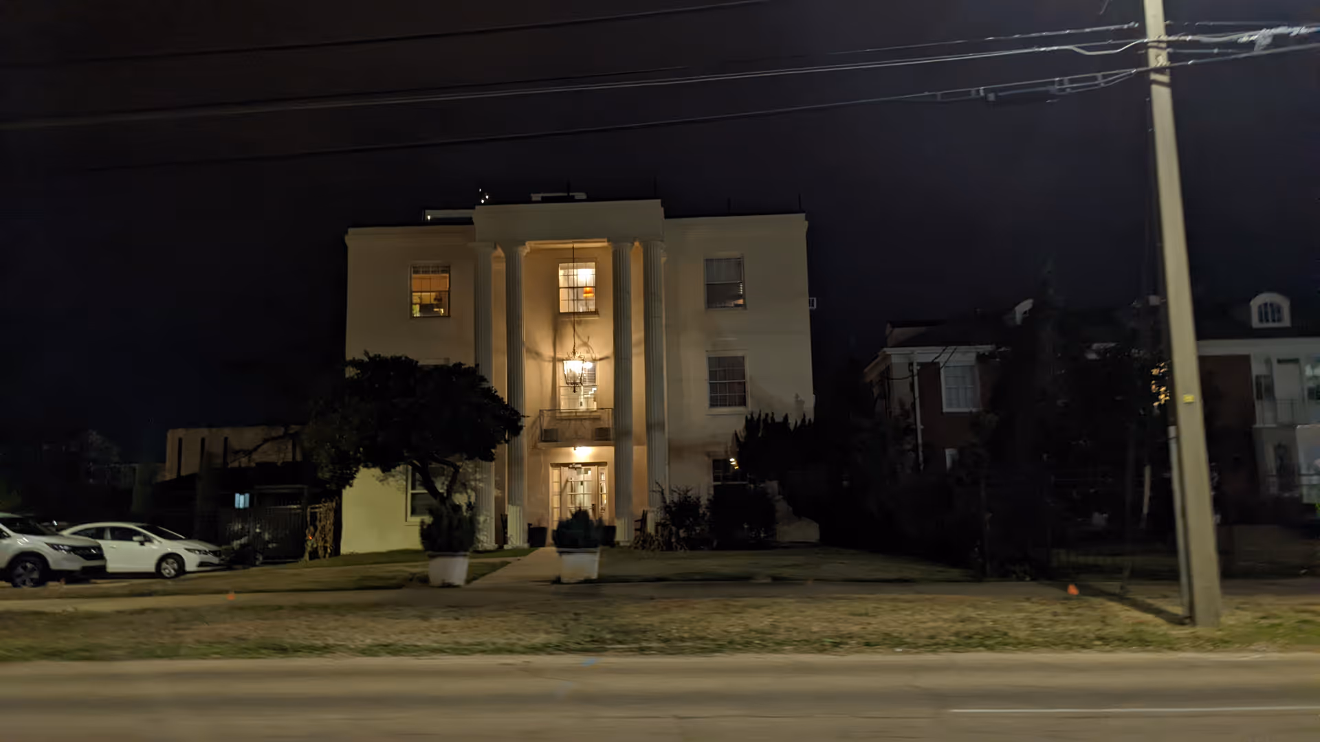 Night exterior view of a three-story senior living facility with a lit central entrance and columns.