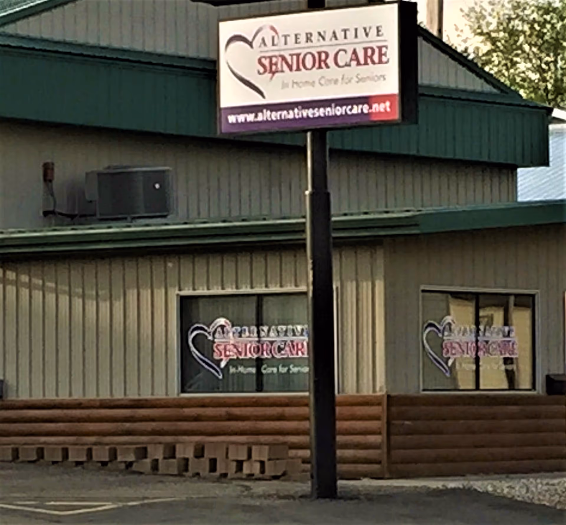Exterior view of a facility with signage reading Alternative Senior Care on a tall pole.