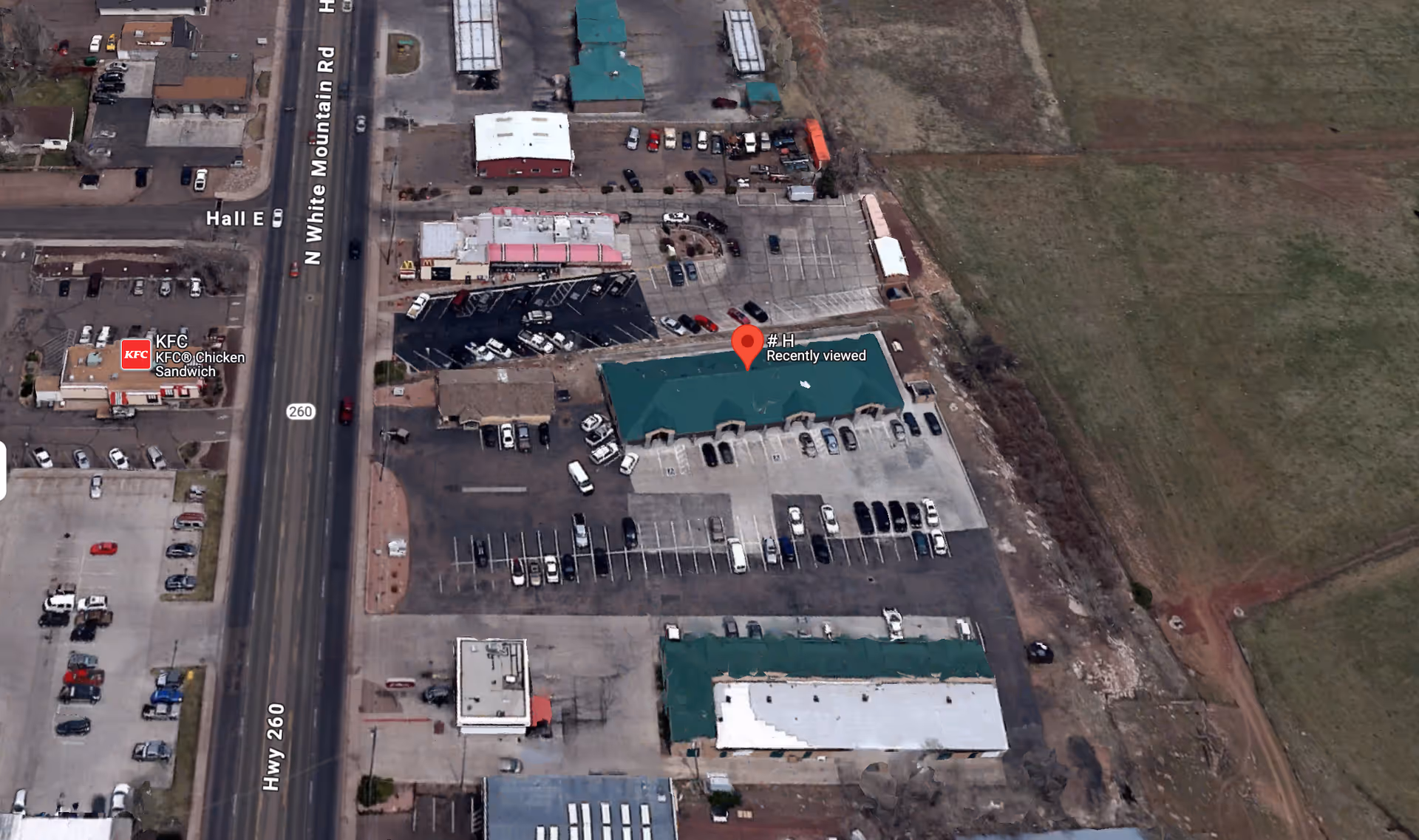 Aerial view of a commercial area with a large parking lot and several buildings.