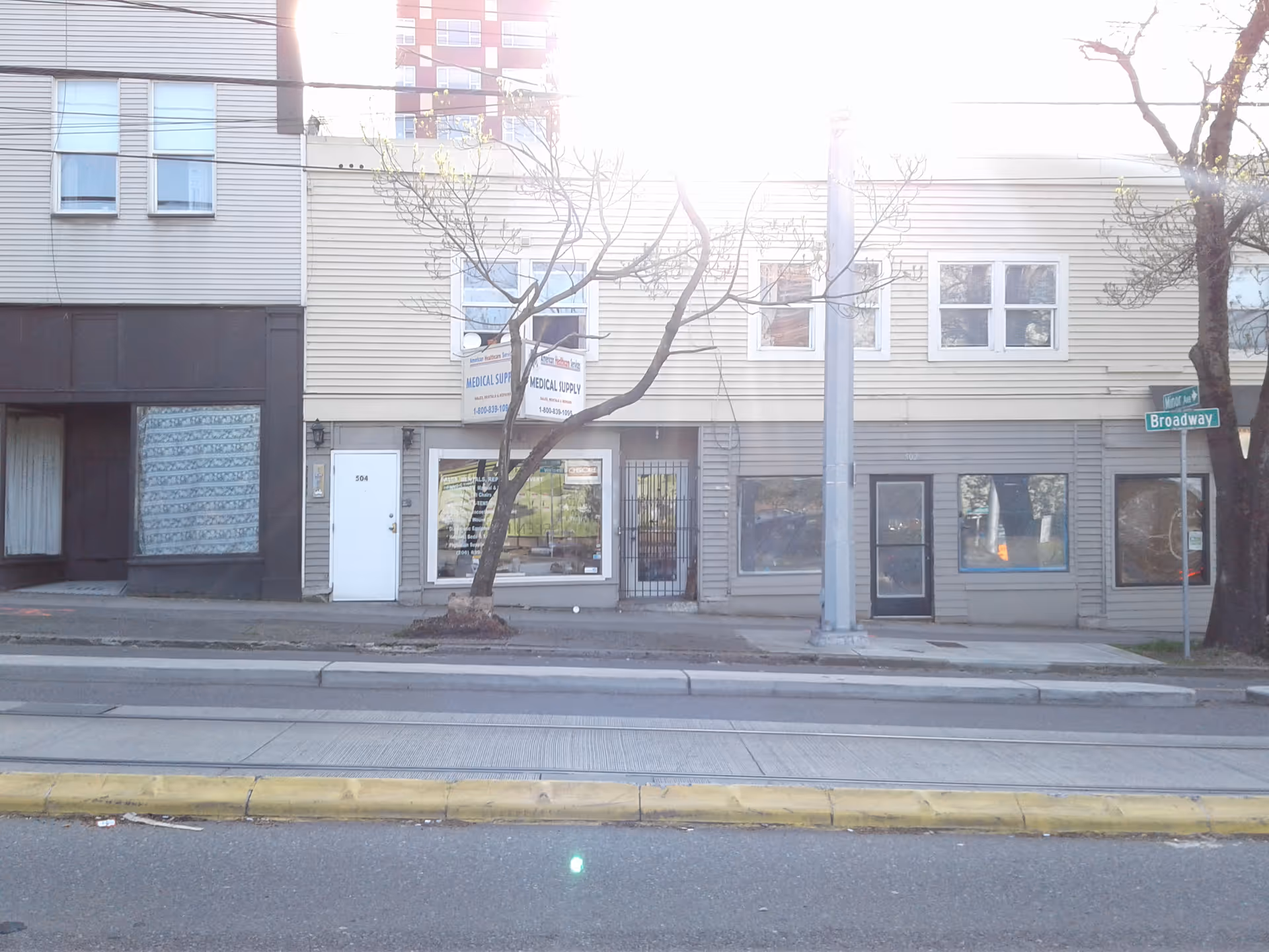 A street-level view of a mixed-use building facade with storefronts and a medical sign on Broadway.