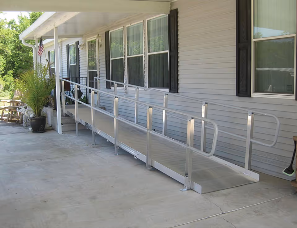 Exterior view of a senior facility with a metal ramp and railing along the walkway.