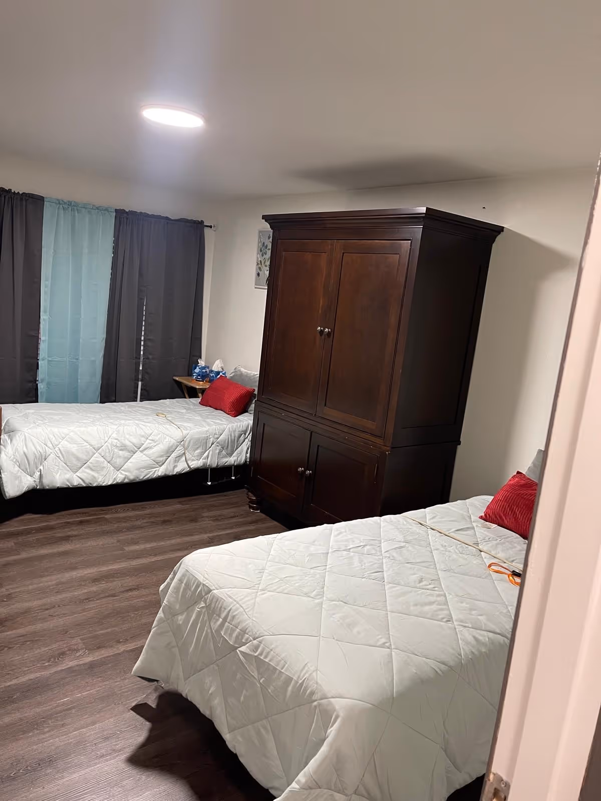 Two twin beds in a shared bedroom with a dark wardrobe between them.