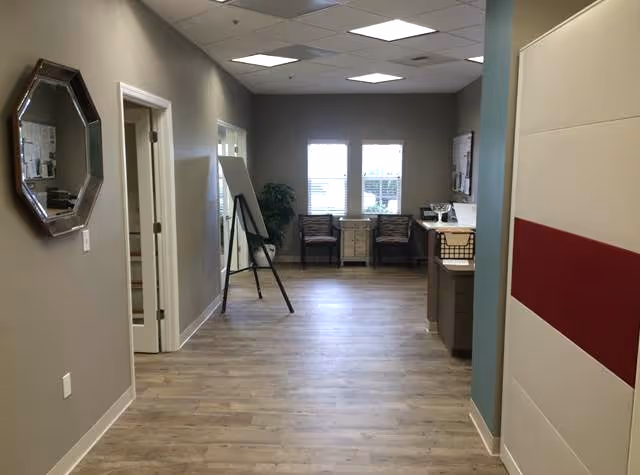 Neutral hallway with seating area at far end, bulletin boards, and a counter along right wall.