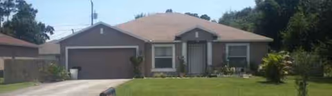 Single-story house with a two-car garage, driveway, and front lawn.