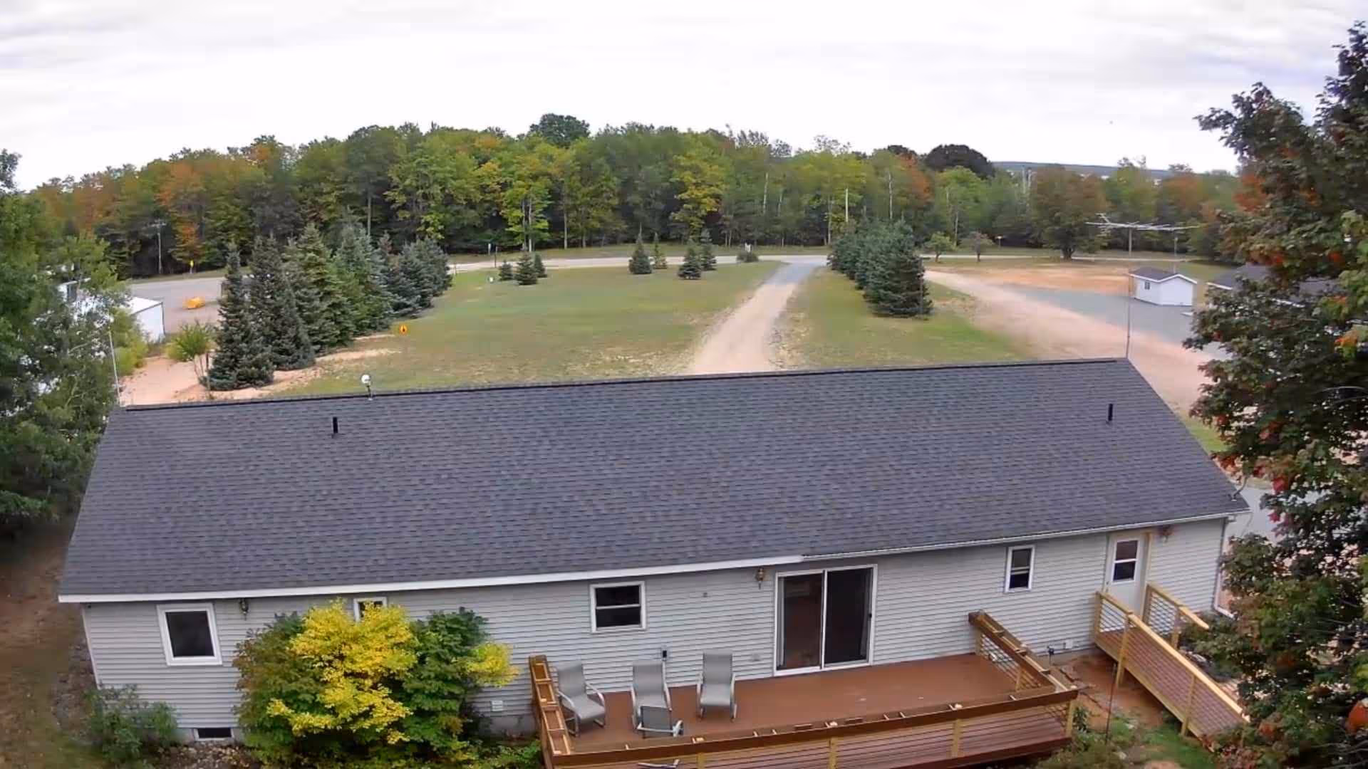 Single-story assisted living facility exterior with a wooden deck and surrounding trees.