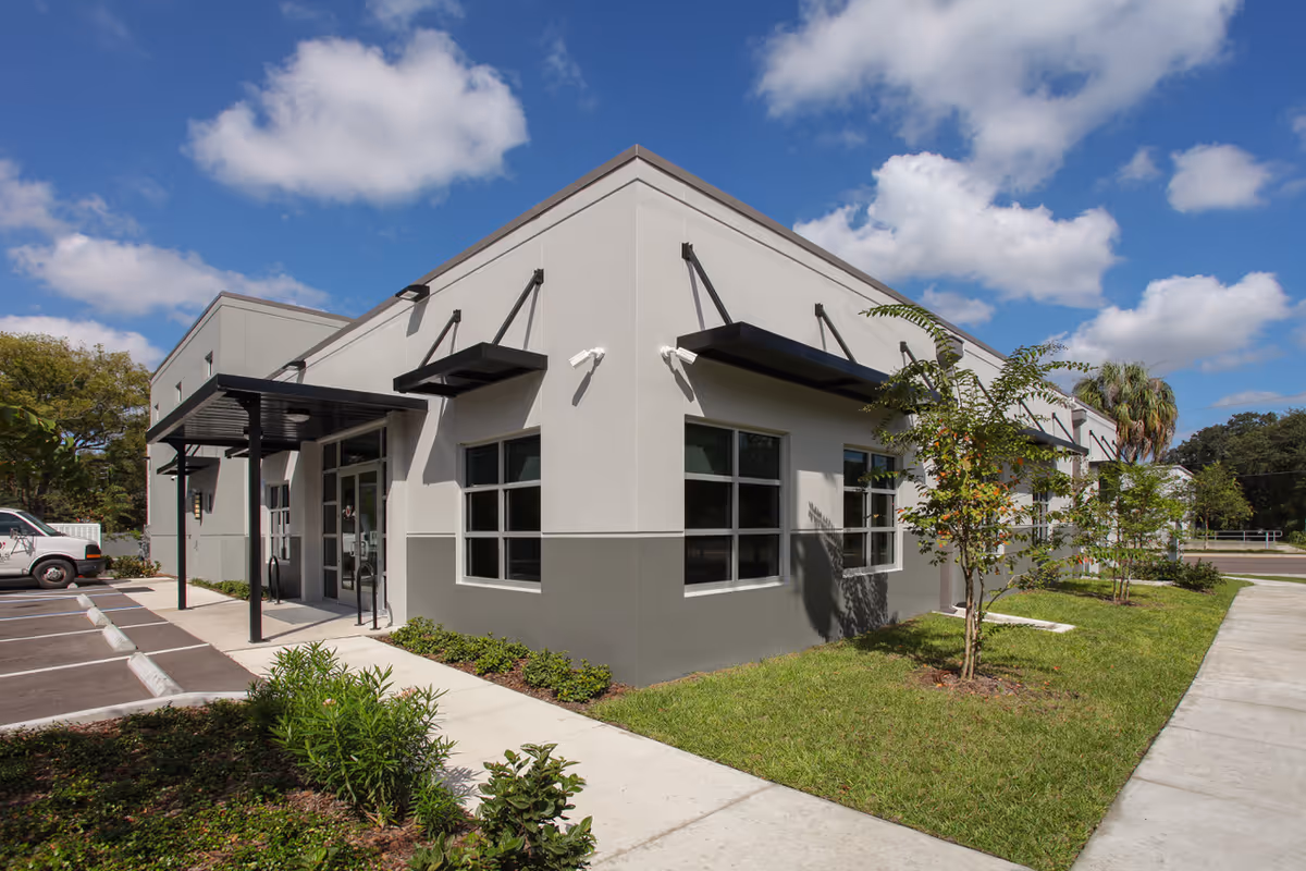 Exterior view of a modern senior facility with parking and landscaped frontage.