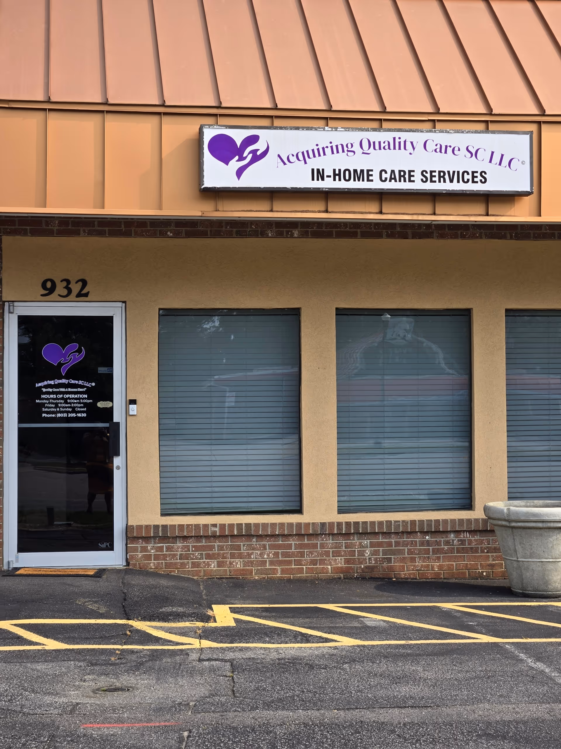 Front exterior of a beige building with a purple sign for Acquiring Quality Care