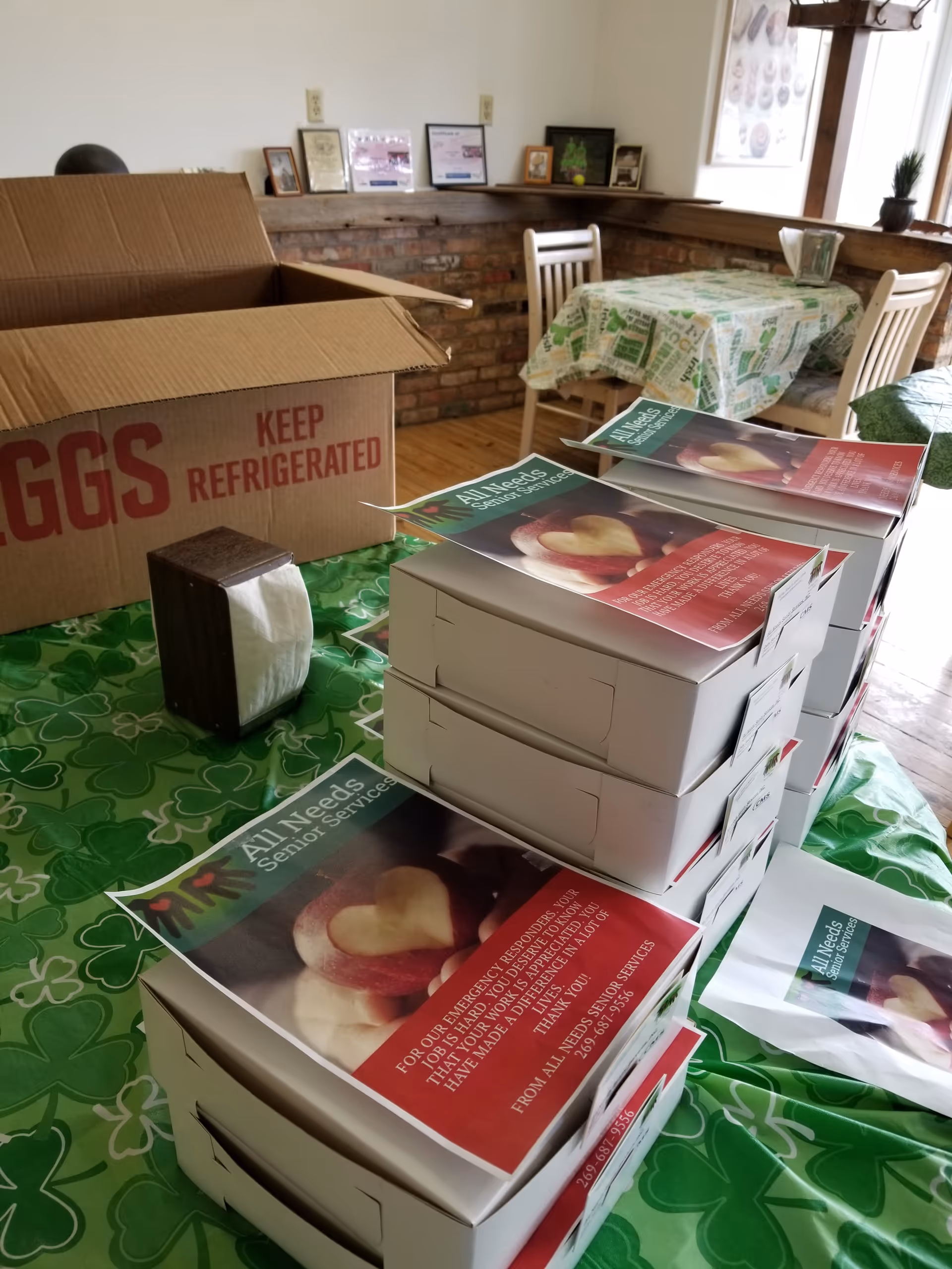 Cardboard egg box and stacked All Needs Senior Services brochures on a table.