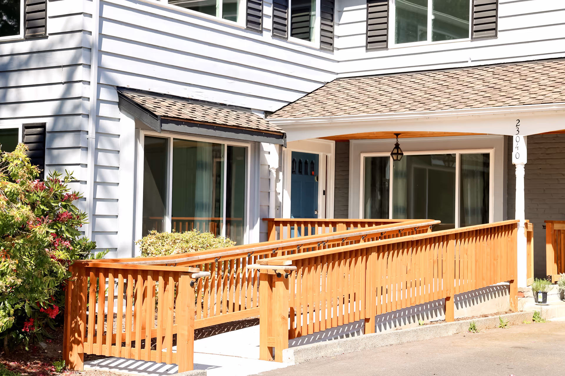 White senior living building front with wooden ramp and porch railing