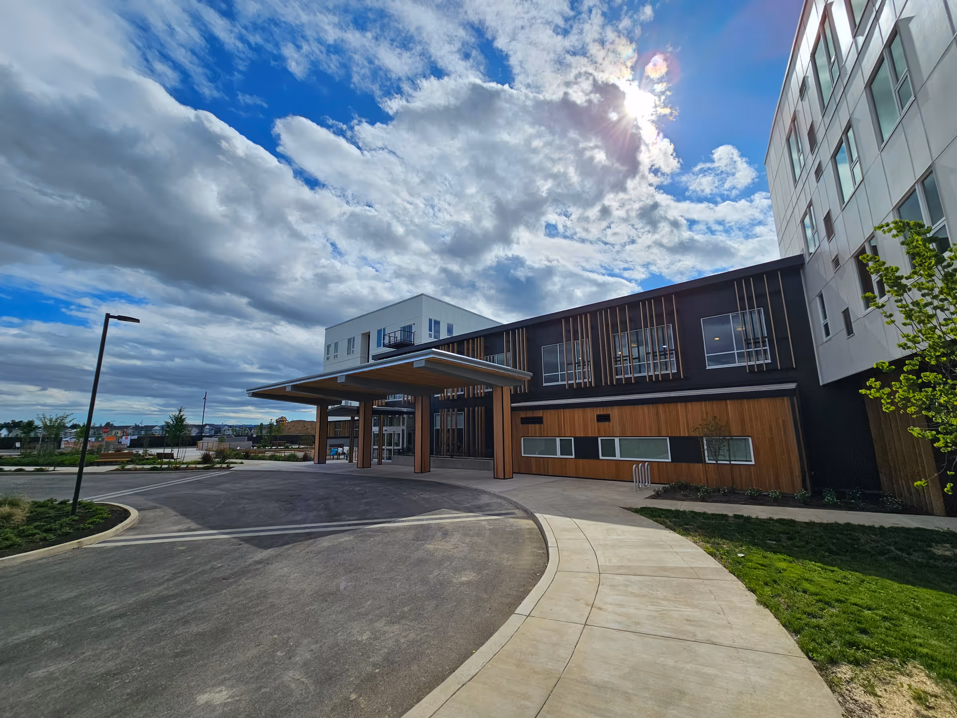 Modern senior living facility exterior with a covered entrance and large windows.