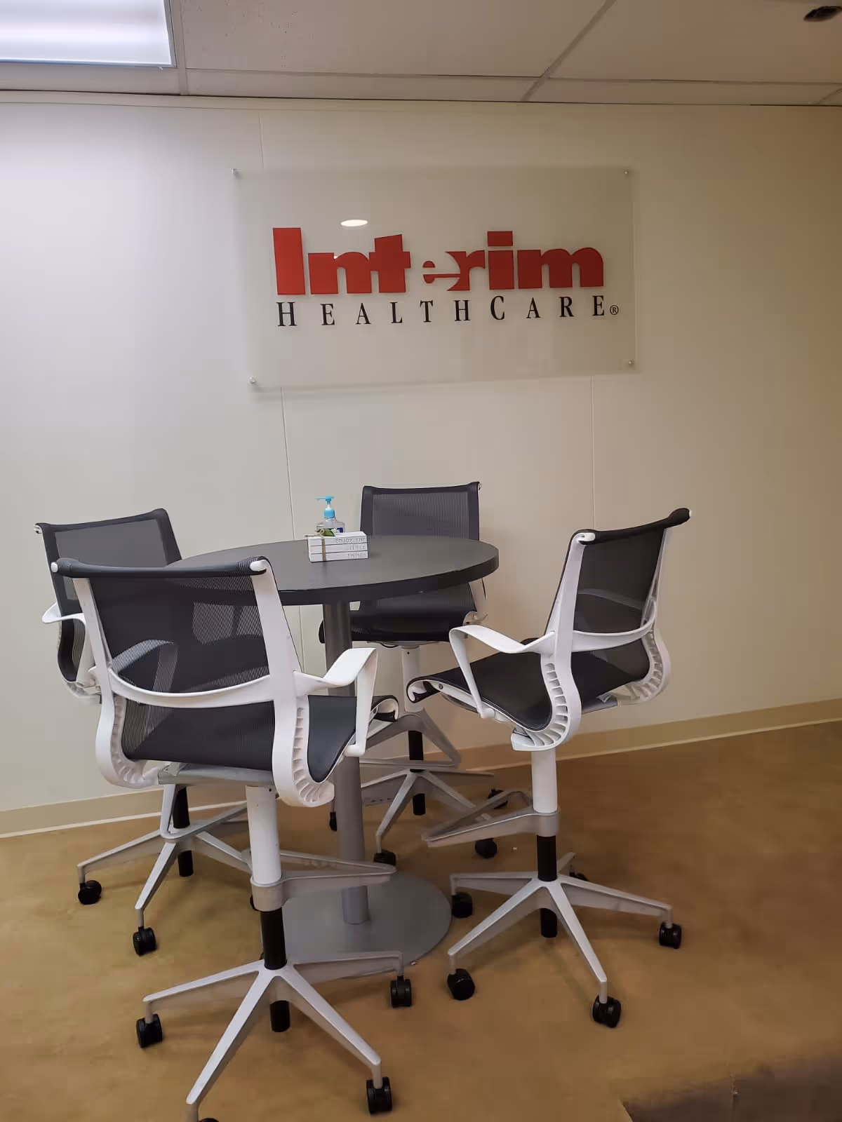 Round table with four ergonomic chairs in a reception area interior with Interim HealthCare sign