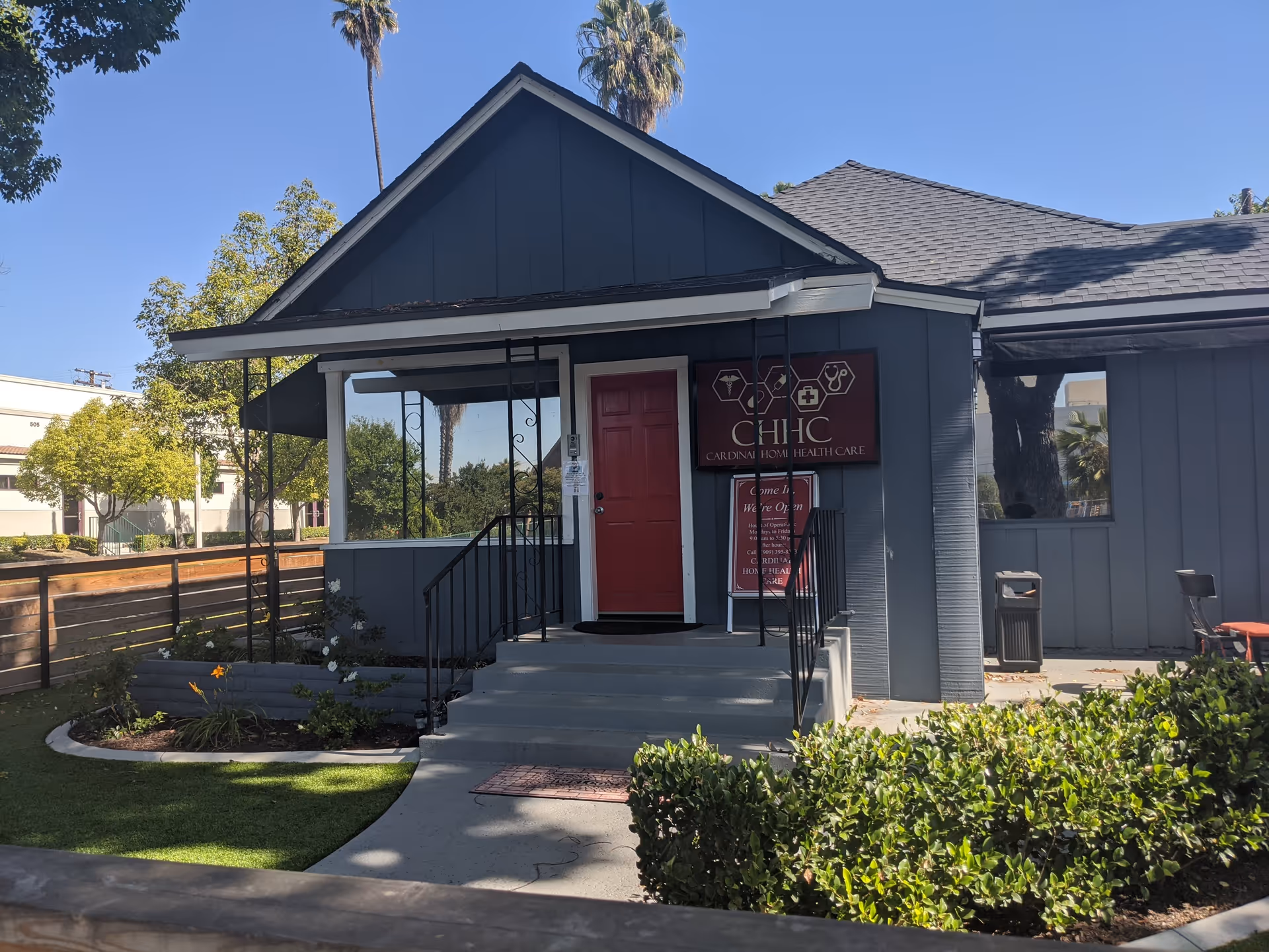Gray, single-story building exterior with a red door and CHHC Home Health Care sign.