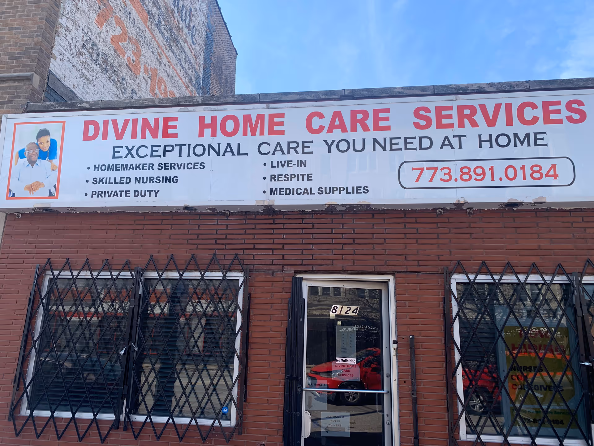 Brick storefront with large Divine Home Care Services sign, phone number, and barred windows.