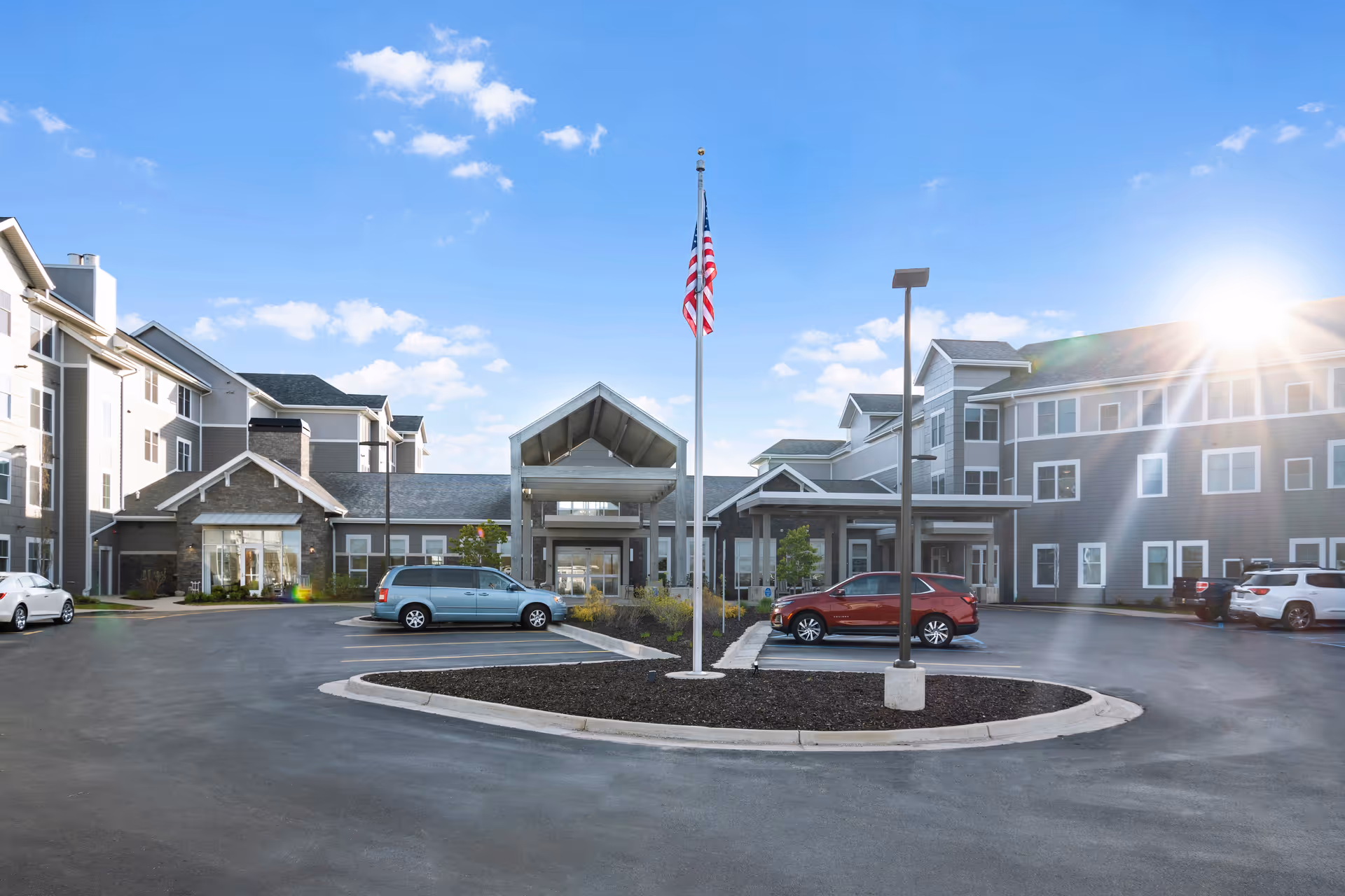 Rivertown Ridge exterior of a senior living facility with circular drive and flagpole.