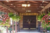 Front entrance of Imperial, a Villa Center, with stone walls, wooden beams, and hanging flowers.