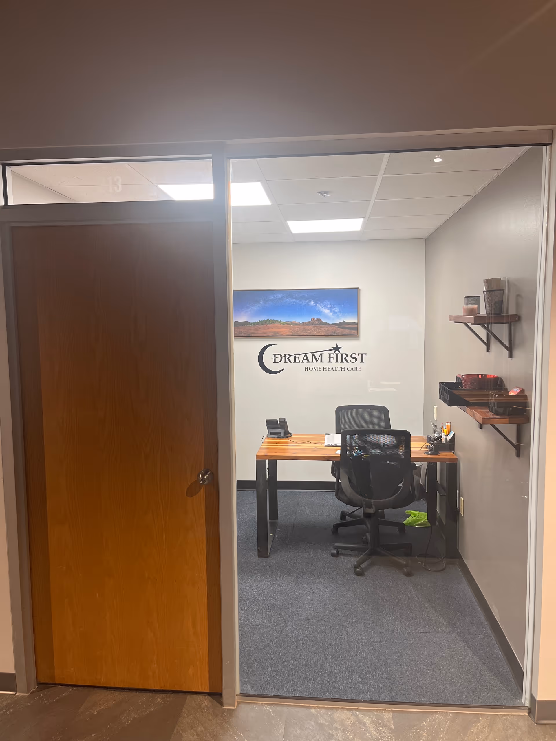 Small office inside Dream First Home Health Care with desk, chair, and wall logo.