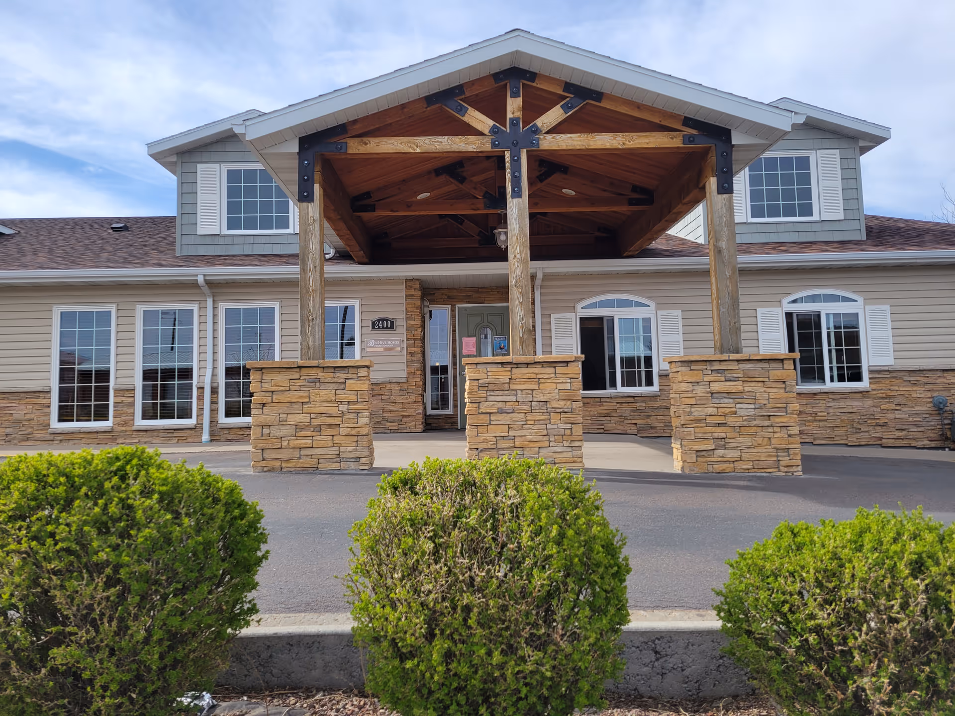 Front entrance of BeeHive Homes of Great Falls with stone pillars and wooden portico.
