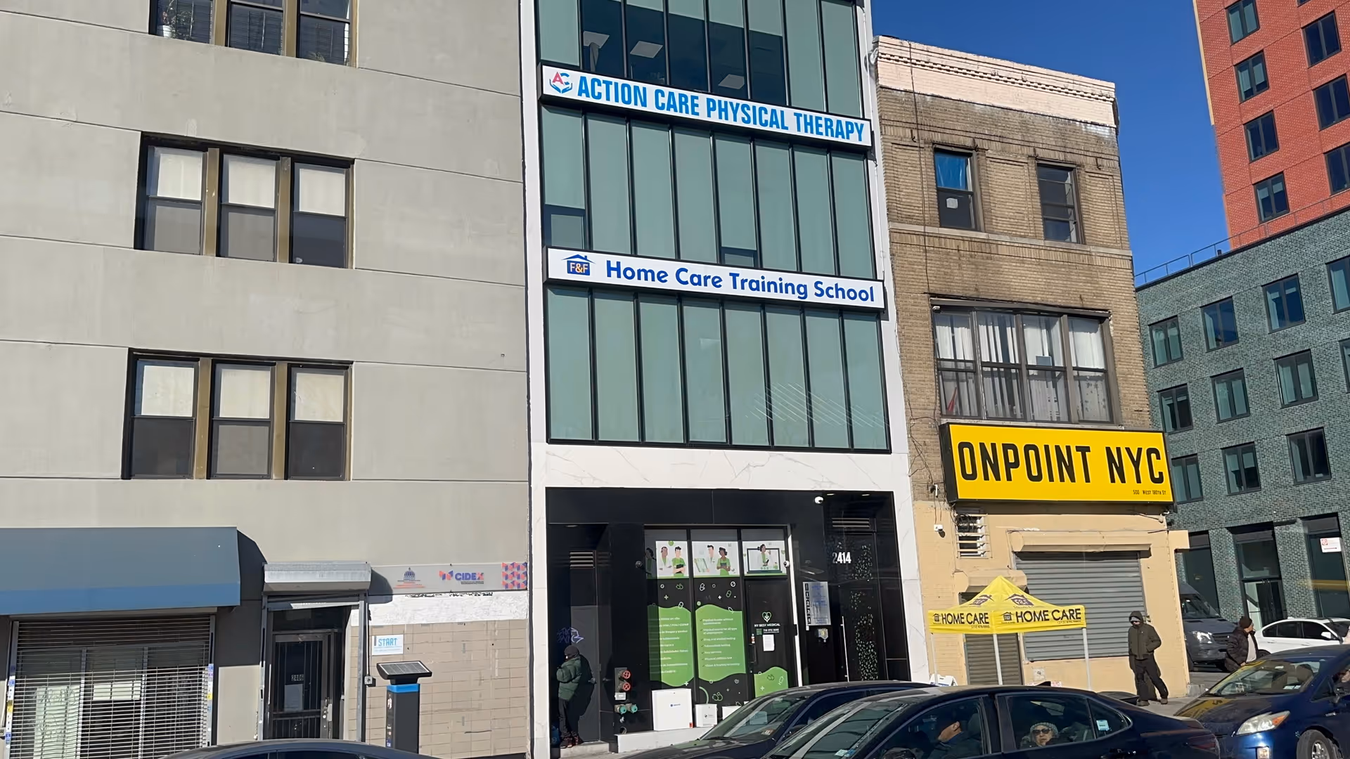Urban street scene with glass-front building and signs for Therapy, Home Care Training, OnPoint NYC.