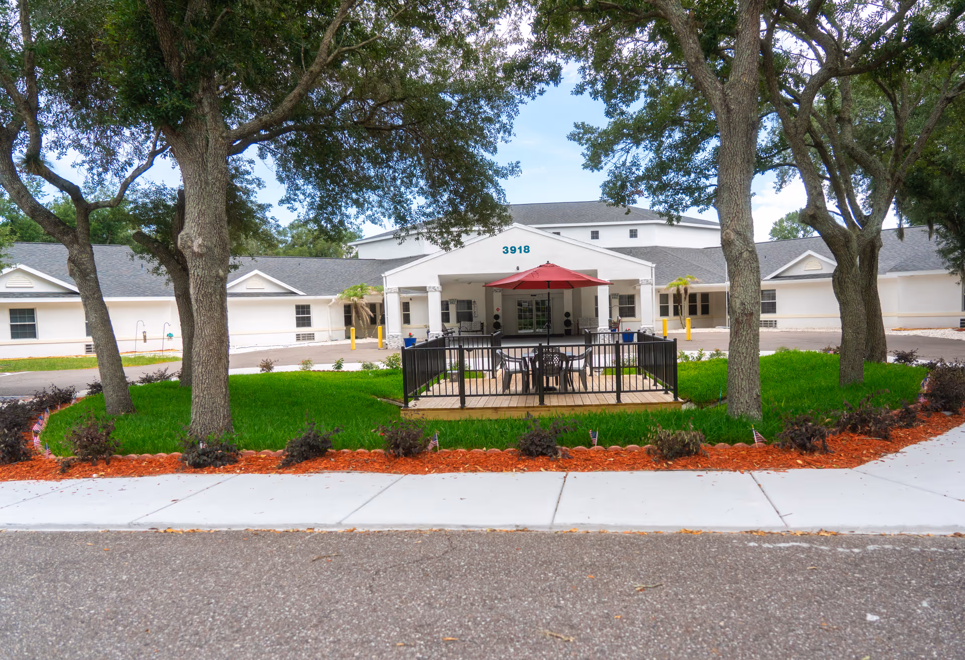 Exterior view of Cloudberry Lodge with a fenced outdoor patio and red umbrella seating.