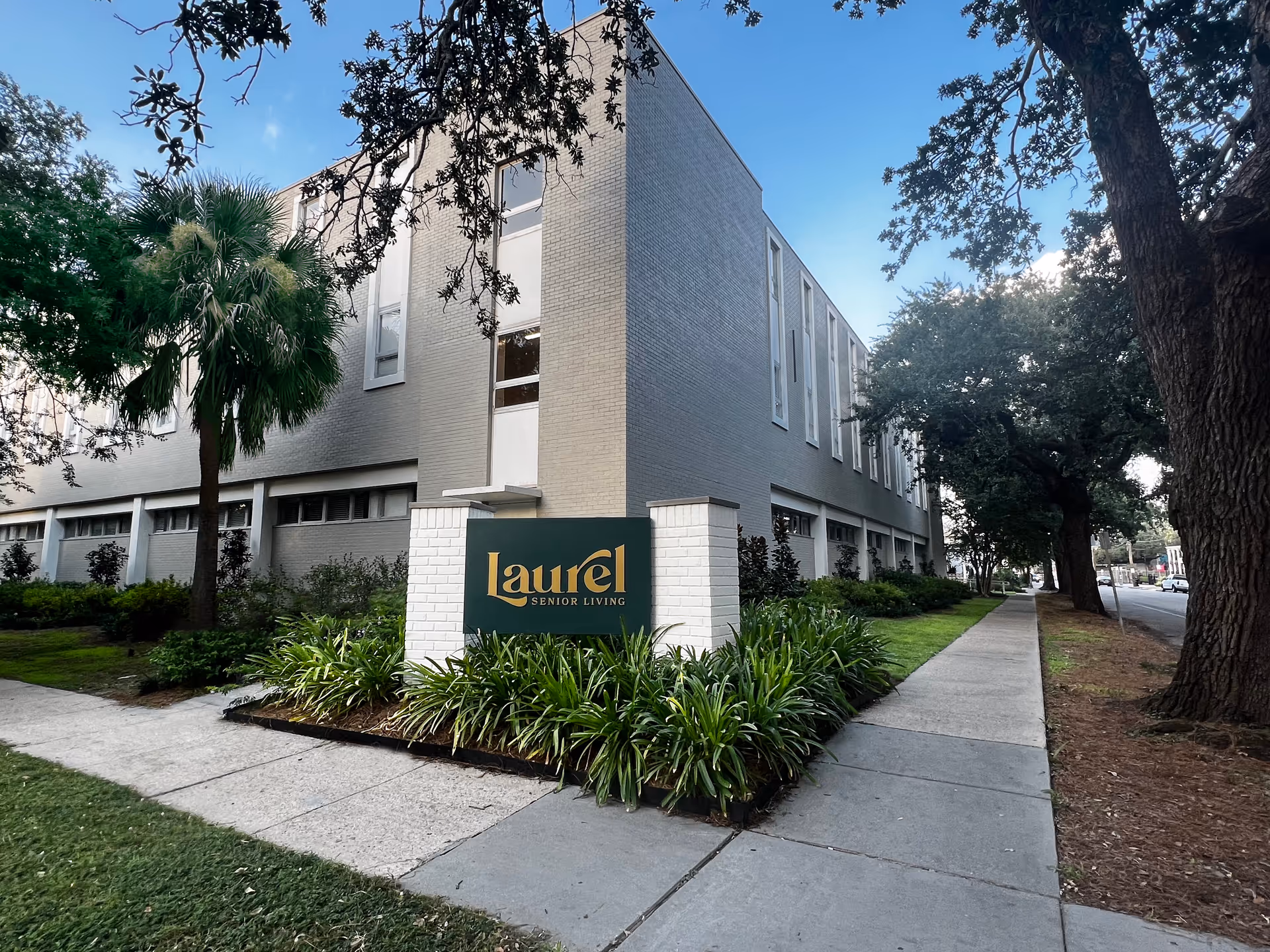 Exterior view of Laurel Senior Living building with sidewalk, landscaping, and sign.