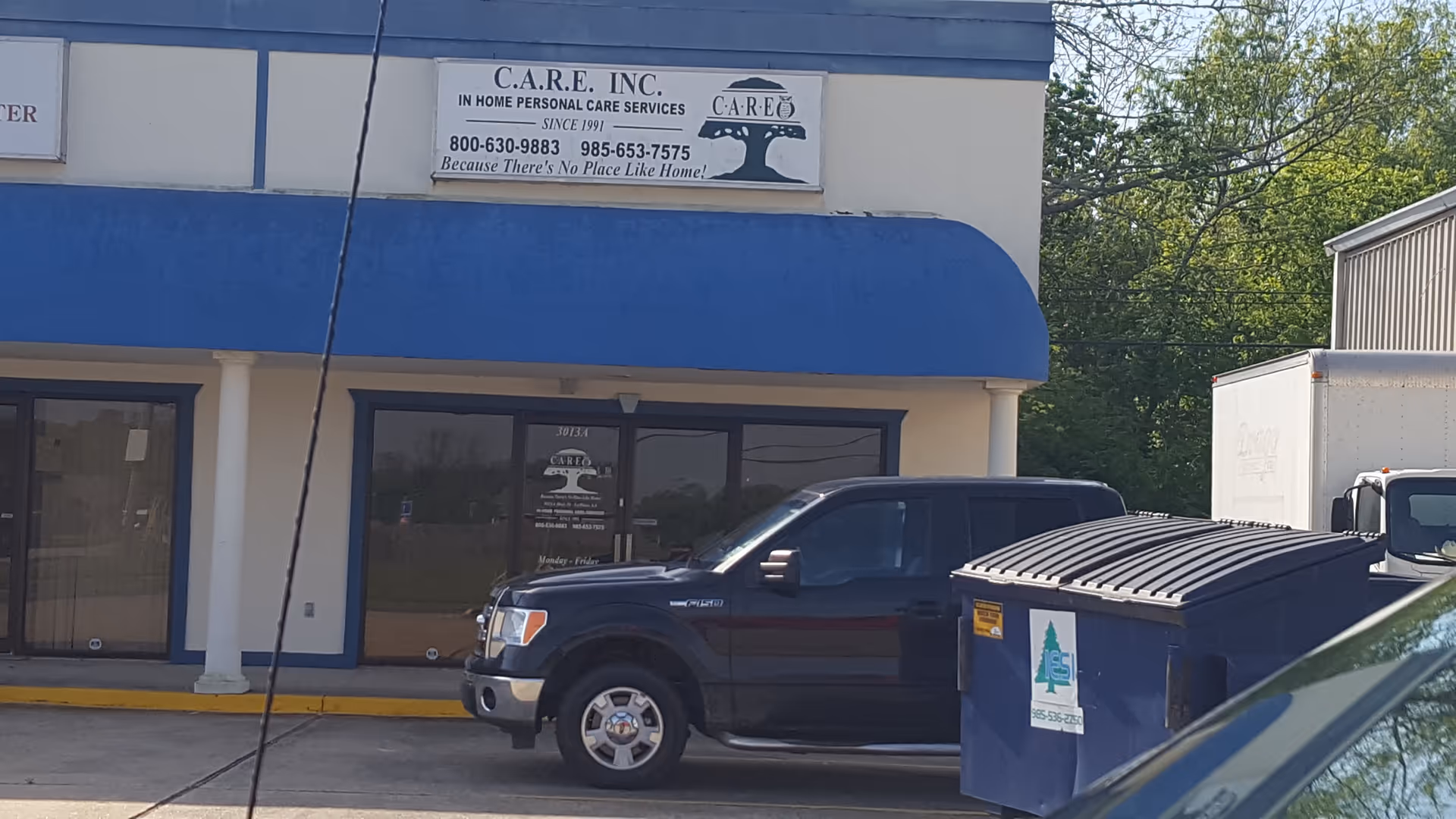 Front of CARE, Inc. building with blue awning and a parked pickup.