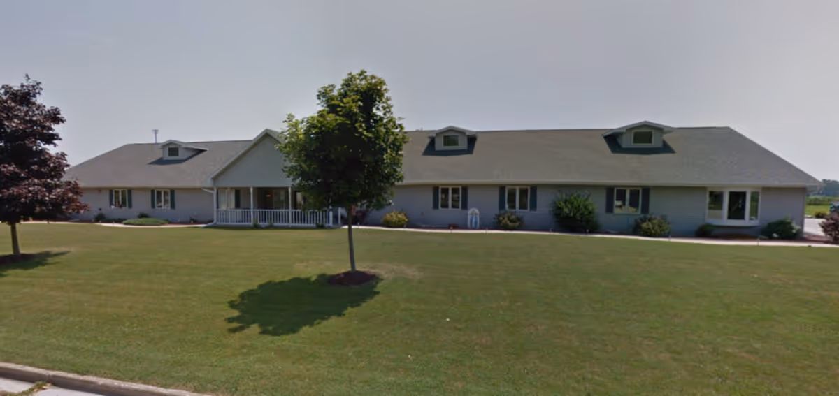 Single-story senior living building with a long front facade and well-kept lawn.