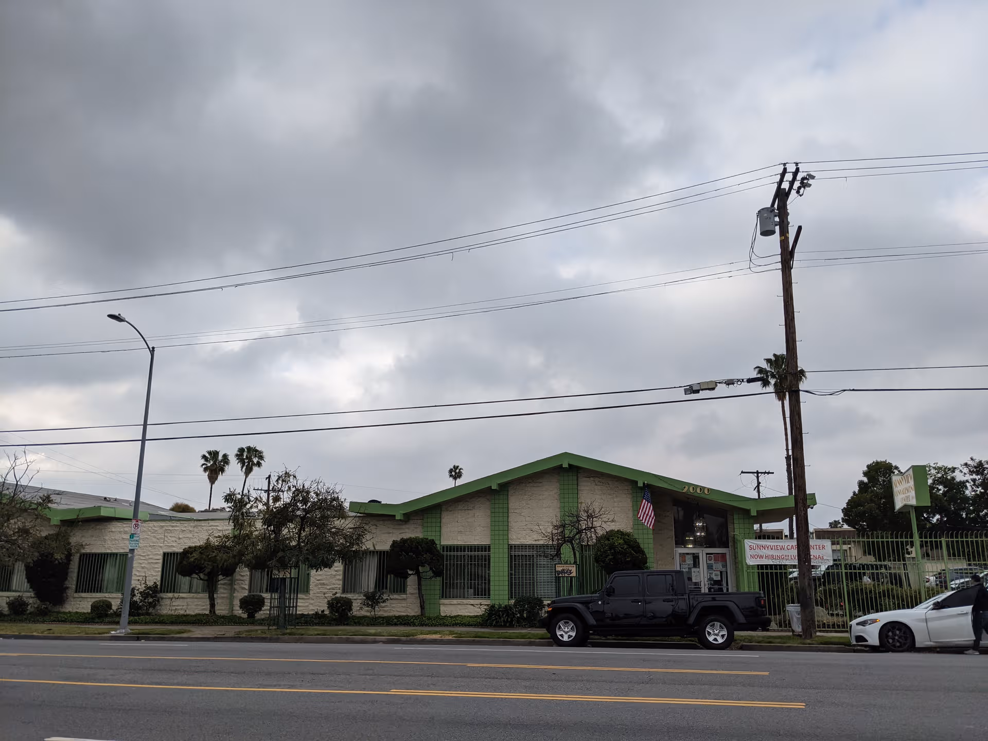 Exterior view of Sunnyview Convalescent Hospital with green trim and parked vehicles.