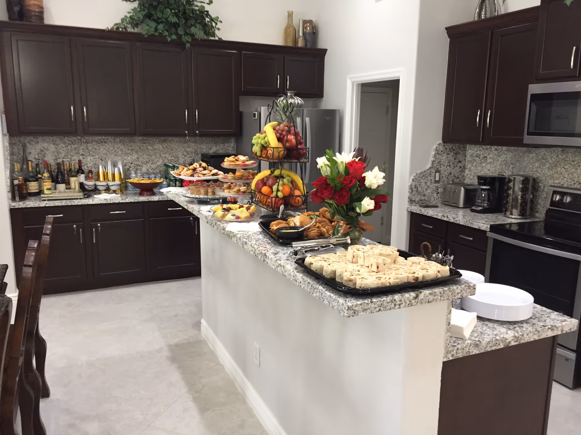 Modern kitchen with dark wood cabinets, granite counters, an island, and a fruit display.