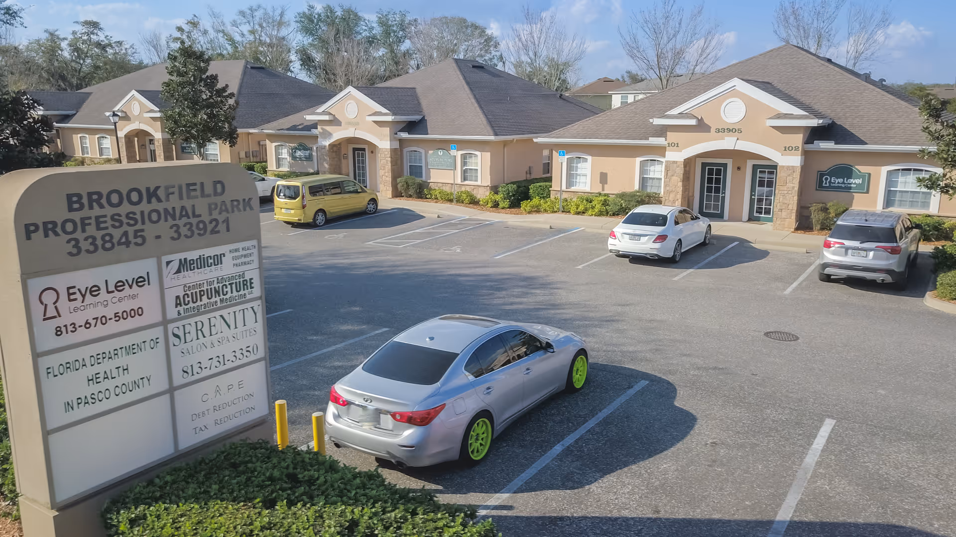 Exterior view of a senior living campus with parked cars and signage.
