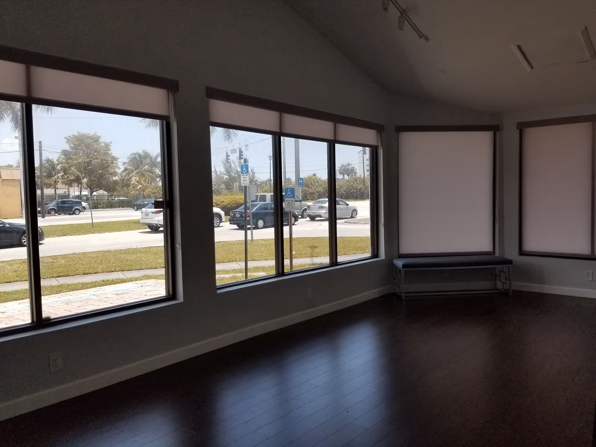 Interior room with large windows, blinds, and a bench along the wall.