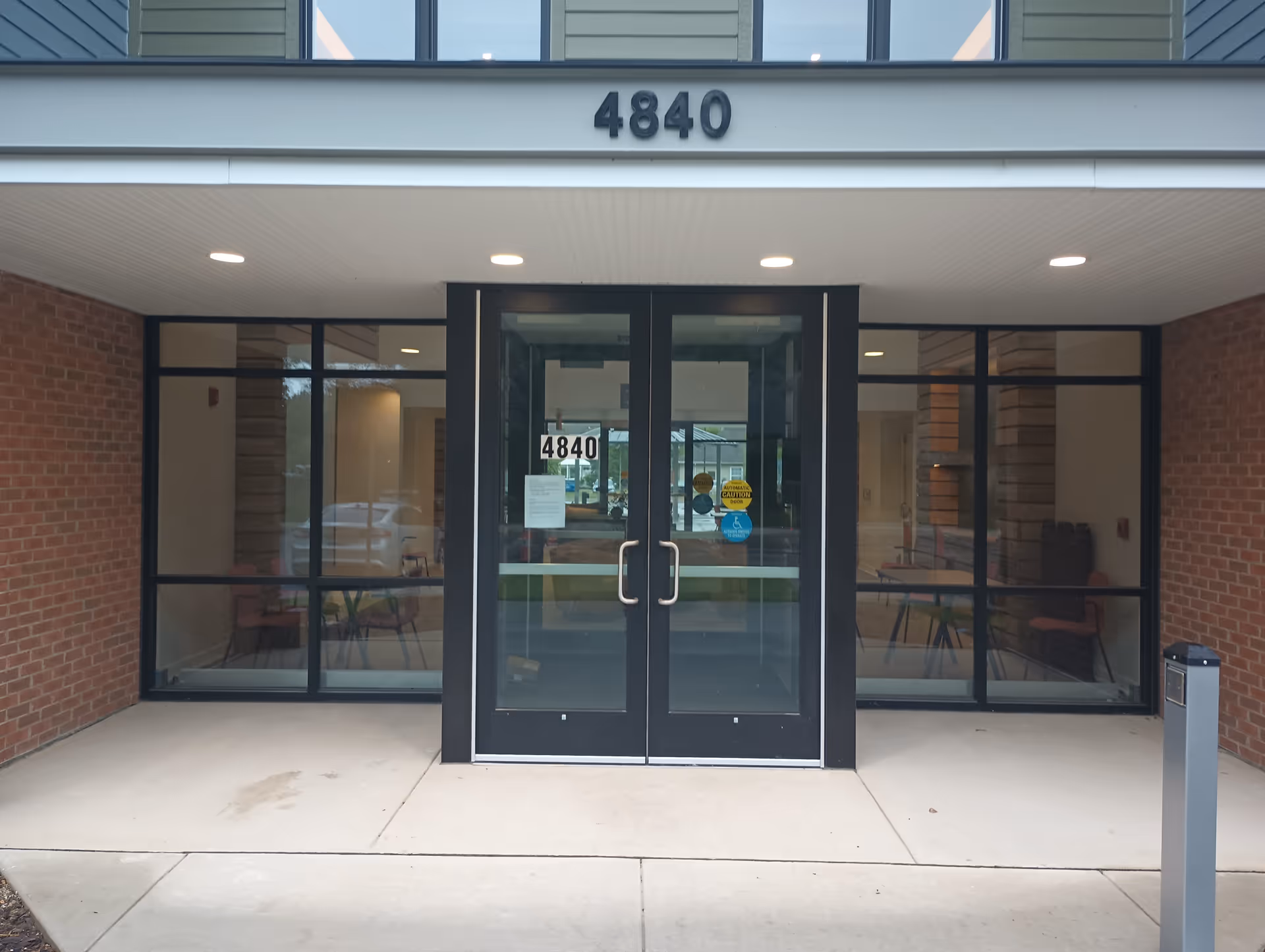 Front entrance of a brick senior living facility with glass doors and 4840.