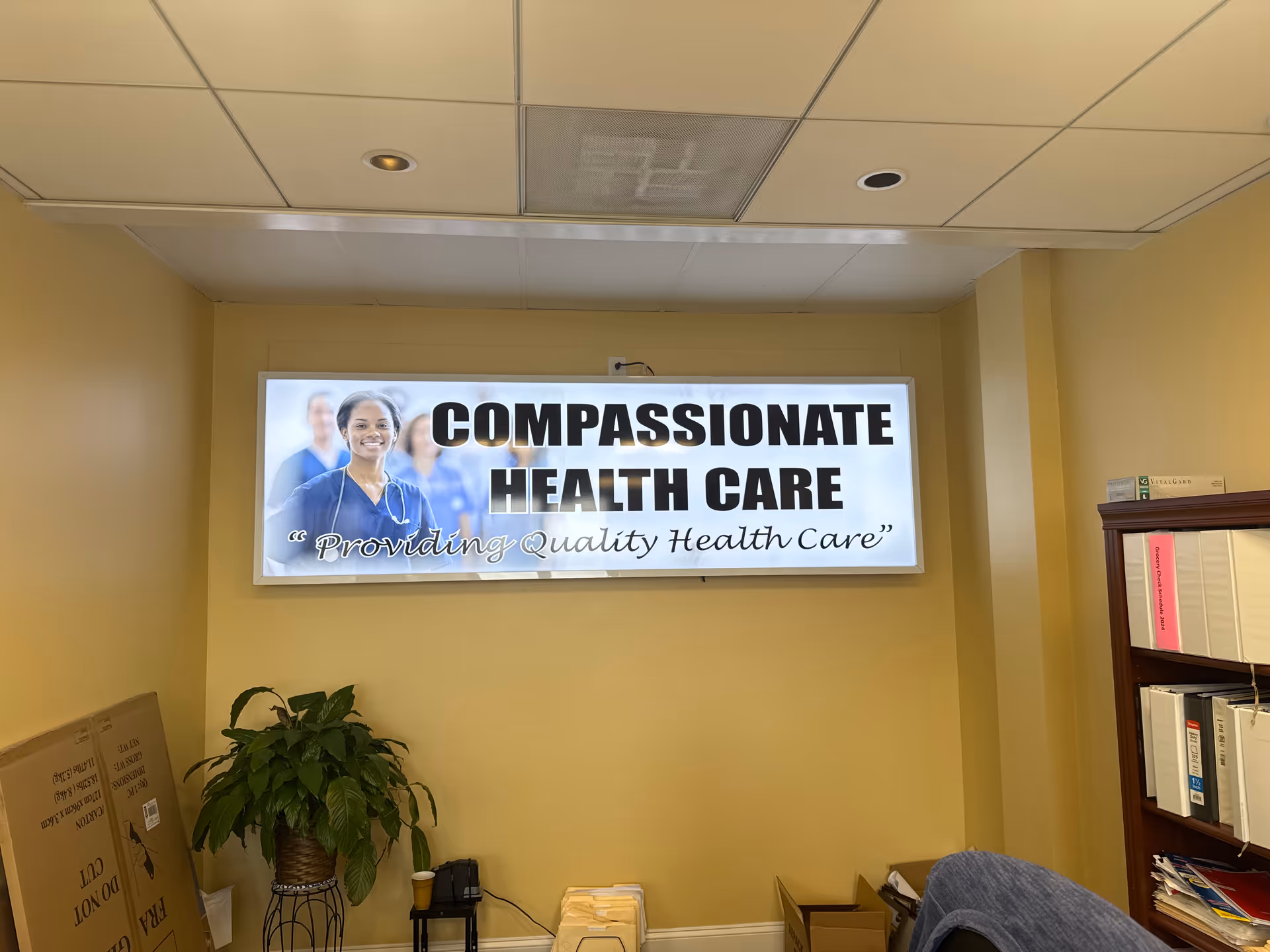 Interior room with a large backlit sign reading Compassionate Health Care on the wall.