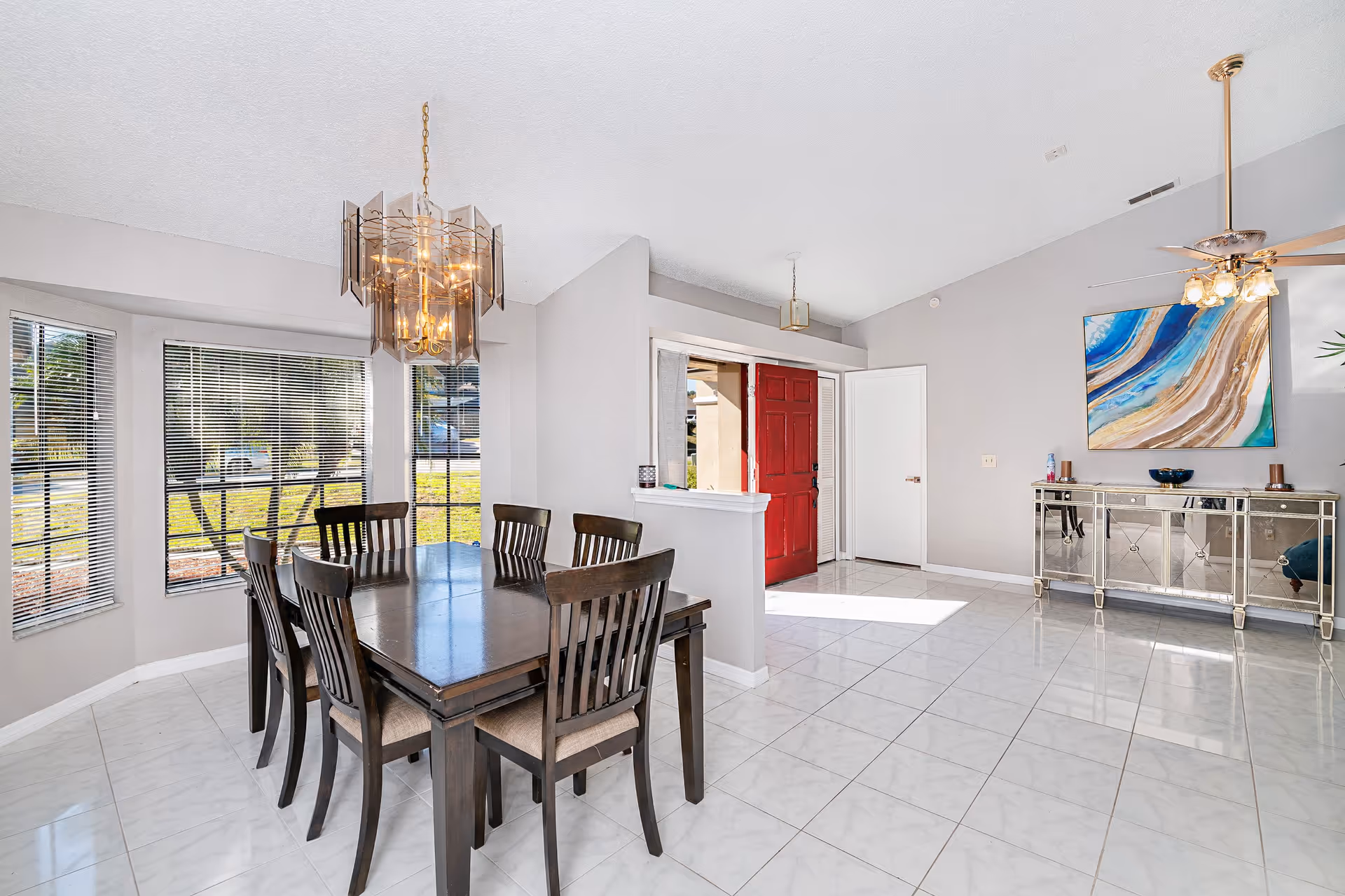 Lamplighter Living dining room with a dark wood table, six chairs, bright windows, and art