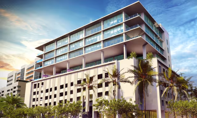 Modern multi-story senior living facility exterior with balconies and palm trees.