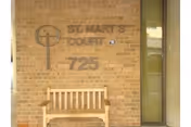 Brick exterior of Saint Mary's Court with a wooden bench at the entrance.
