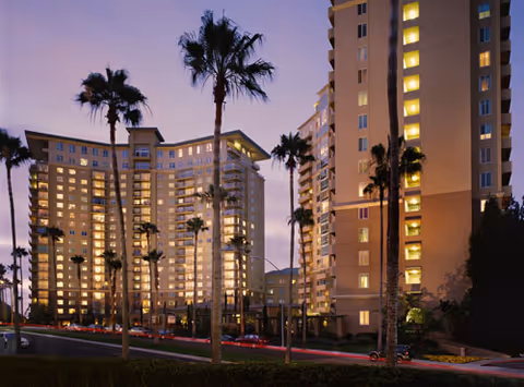 Exterior view of Classic Residence Vi Community with palm trees at dusk.
