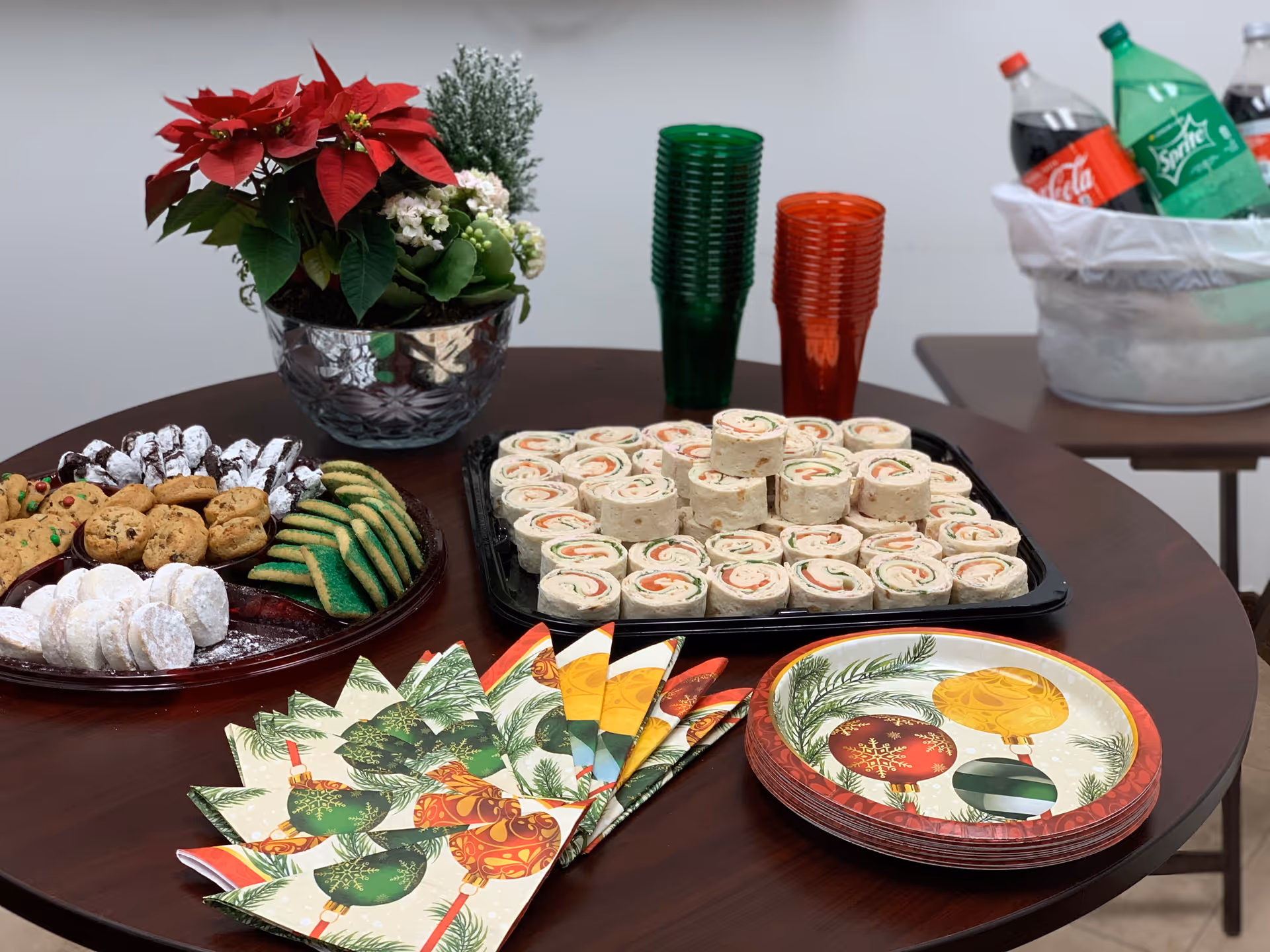 Round table with assorted desserts, snacks, cups, and holiday decorations.