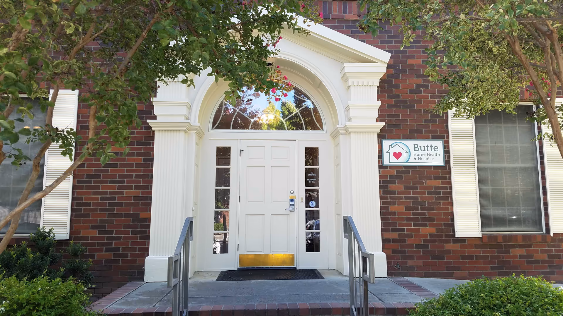 Brick building with white arched doorway and Butte Home Health & Hospice sign.