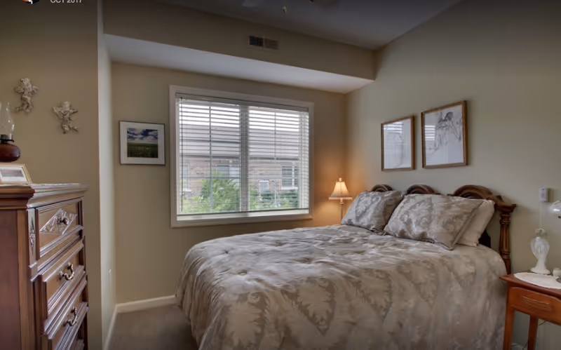 Cozy bedroom with a large bed, window, dresser, and matching nightstands.