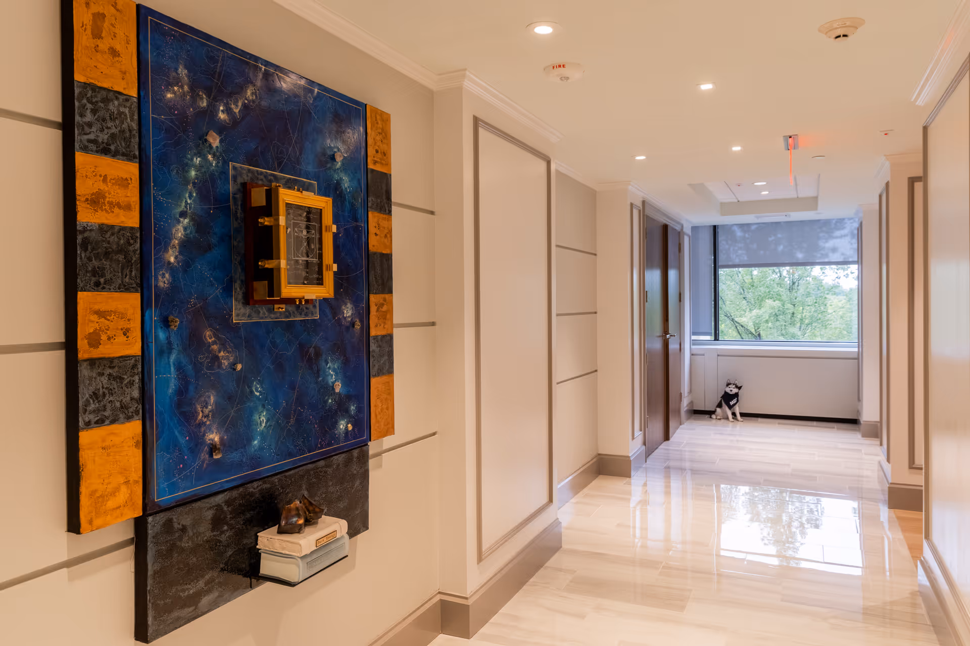 Bright hallway in a senior living facility with bold art and a dog by the window.