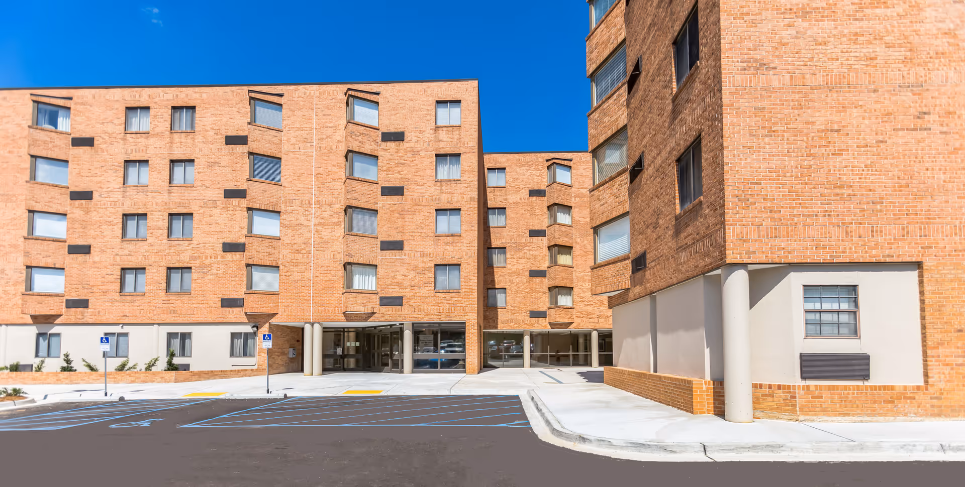 Exterior shot of Lakeland Seniors Apartments front: brick building with entrance and parking.