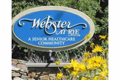 Blue oval sign reading Webster at Rye, with yellow flowers and greenery.