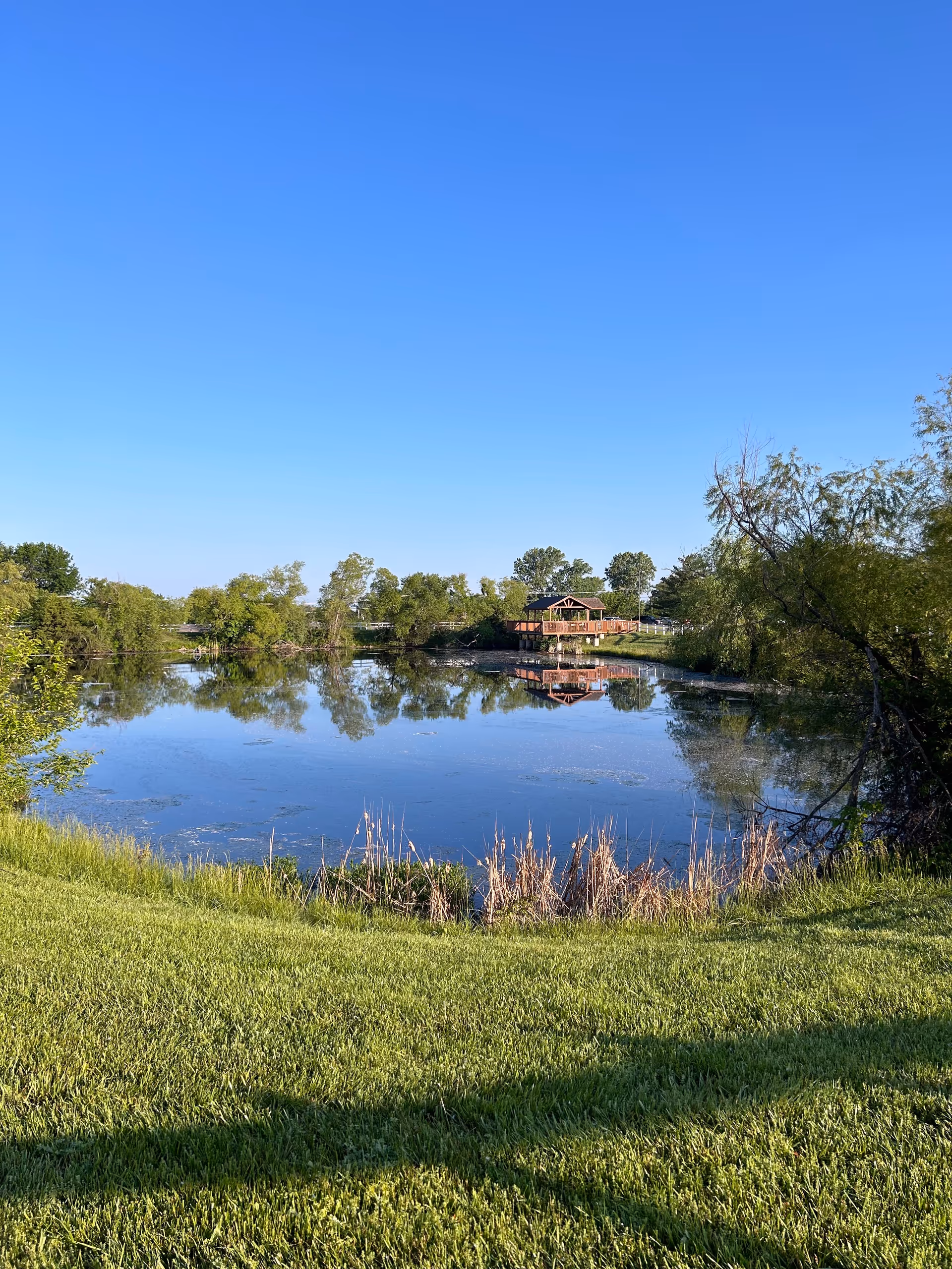 Crown Care Center outdoor scene with pond, trees, and a wooden pavilion reflecting on water.