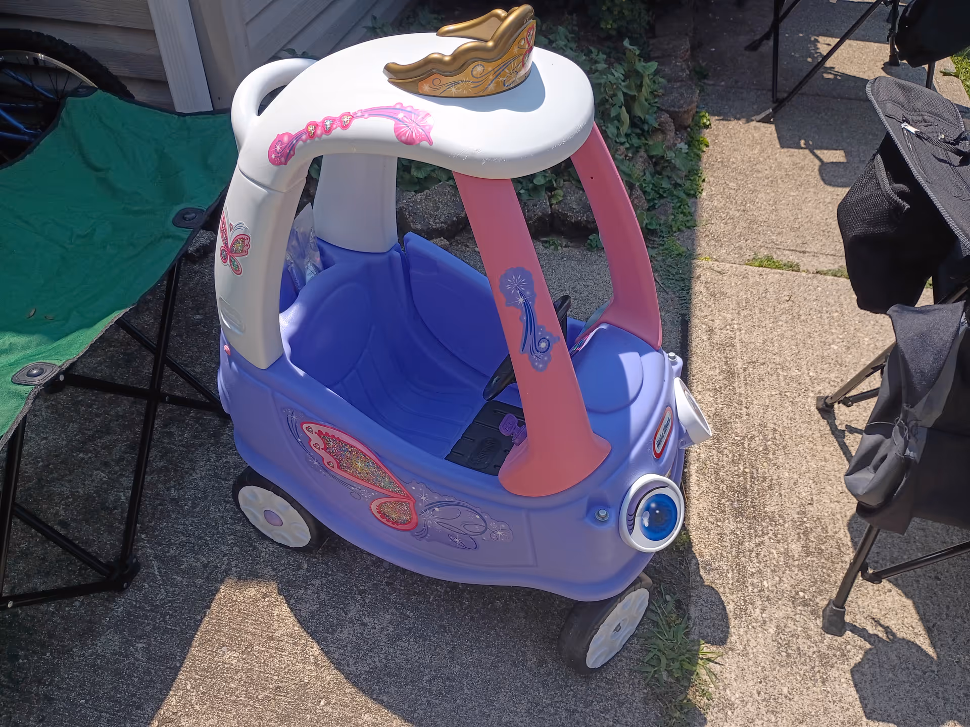 Colorful toy ride-on car outdoors beside a green folding chair.