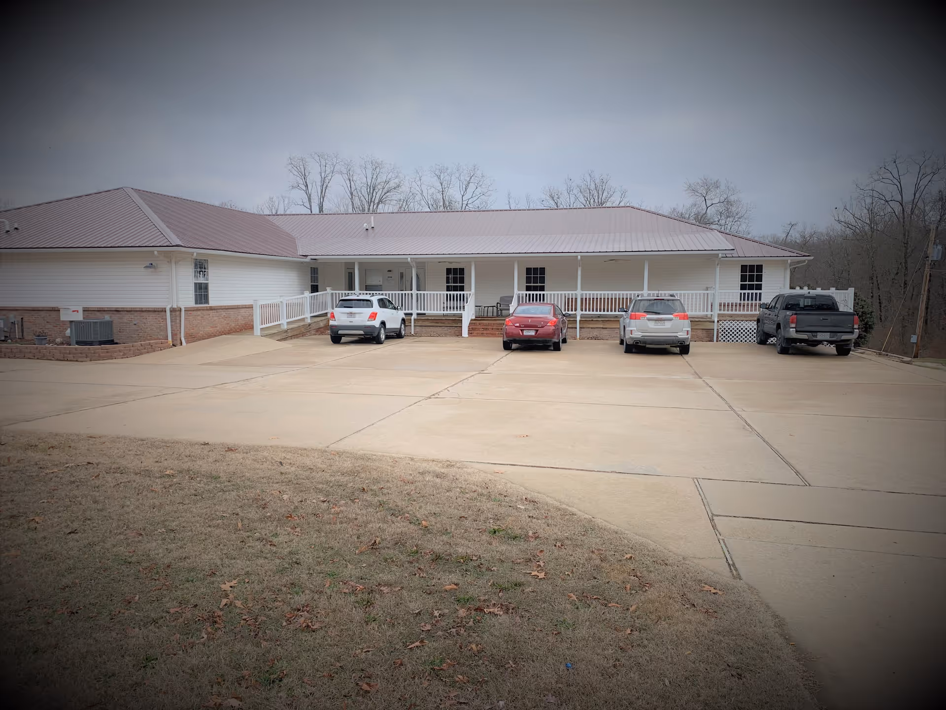 Single-story senior living facility with a covered front porch and several cars parked outside.