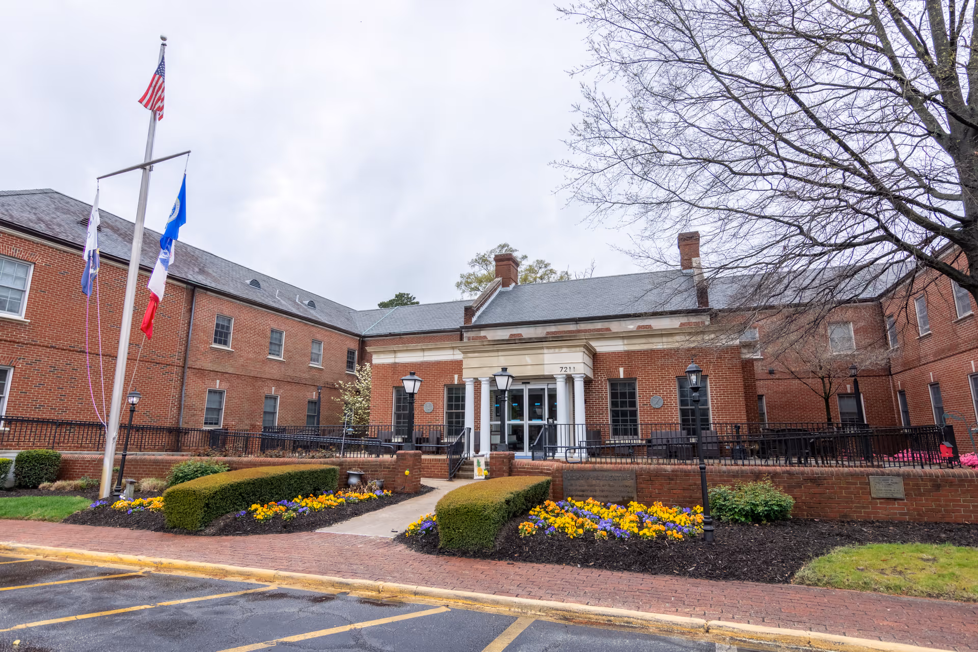 Exterior view of Commonwealth Senior Living at the Ballentine, brick front entrance with flags.