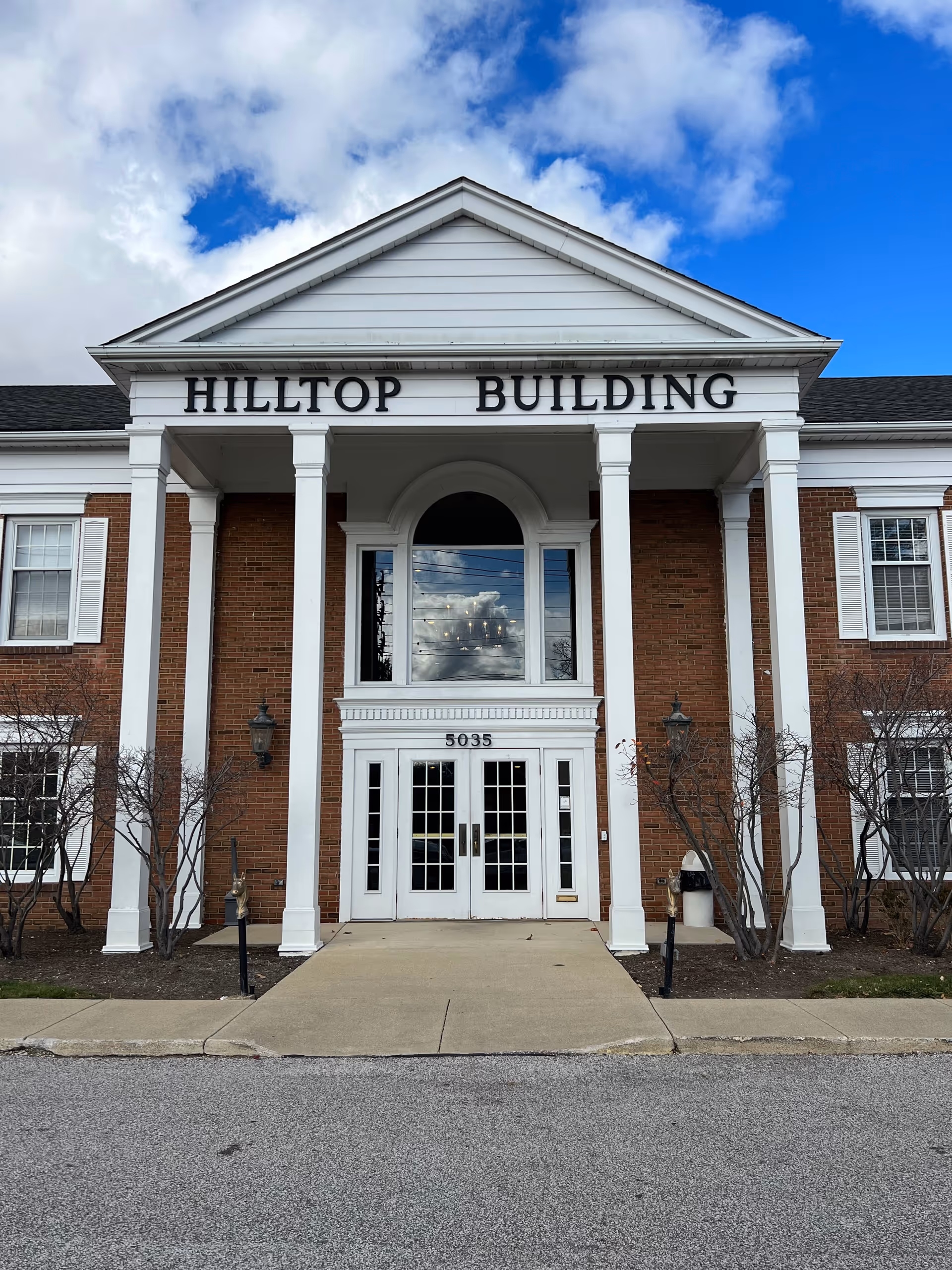 Front view of a brick senior living building with tall white pillars.