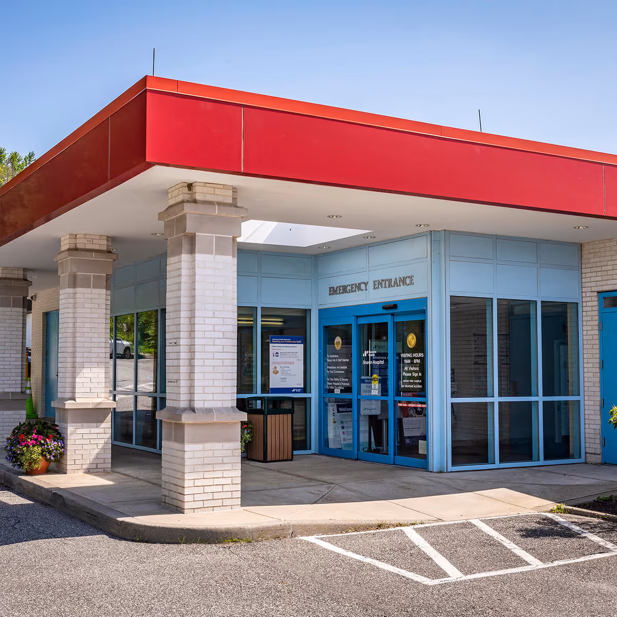 Exterior view of a building entrance with a red canopy and blue doors.
