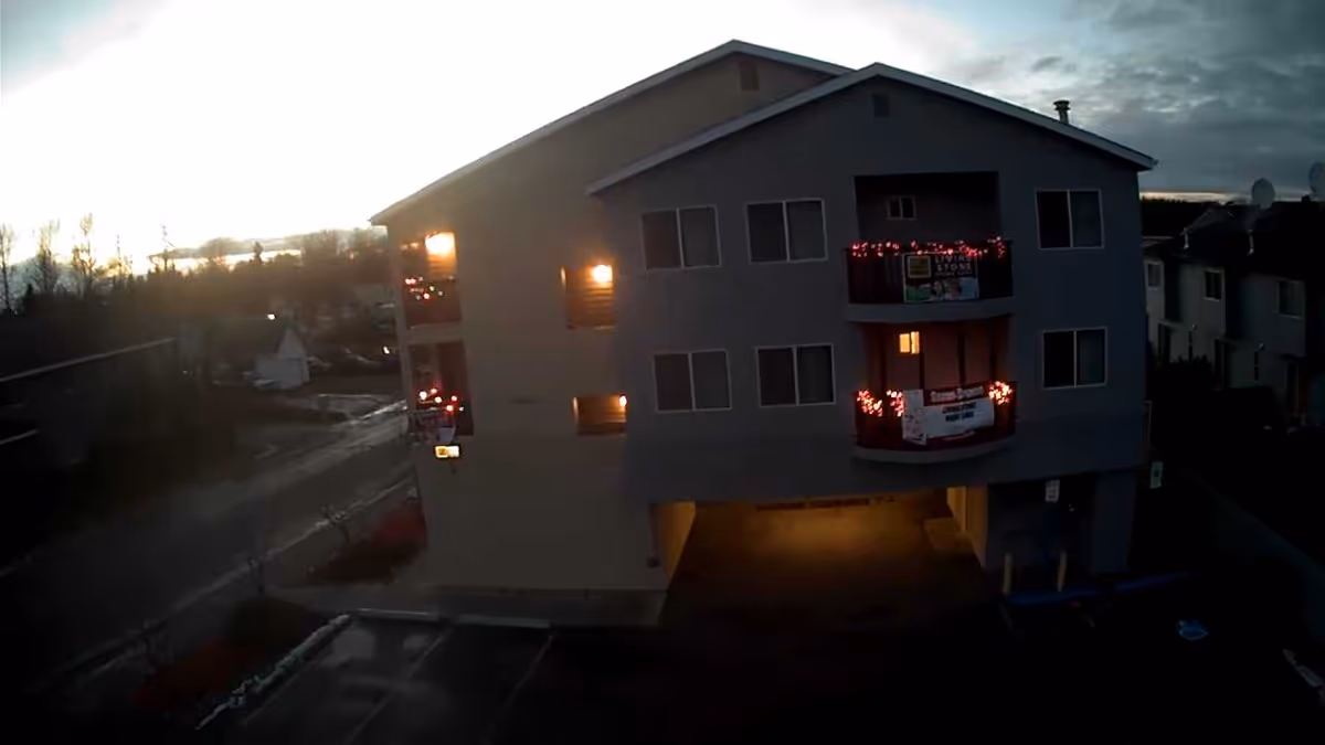 Dusk exterior view of a multi-story senior living building with lit balconies.