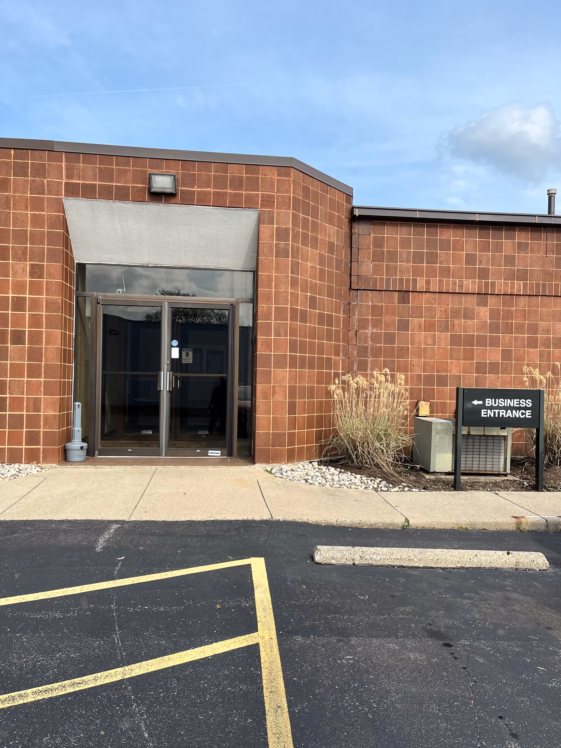 Brick building exterior with glass doors, walkway, and a 'Business Entrance' sign.